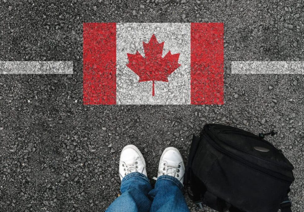 shoes-next-flag-canada A man with a shoes is standing next to flag of Canada.